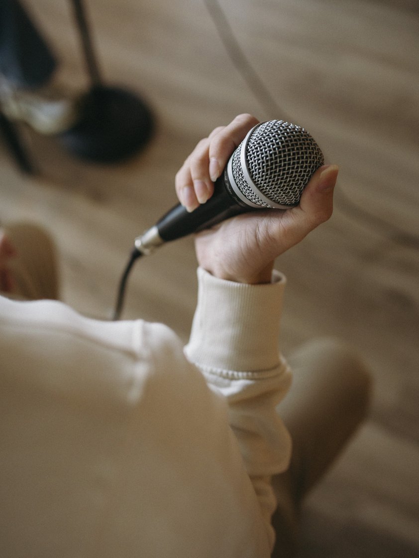 Mano sujetando un micrófono durante una clase de Canto Escuela